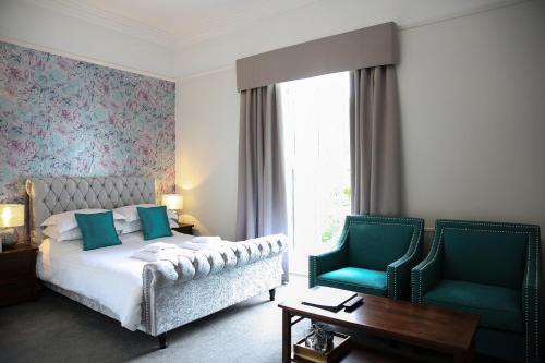 a bedroom with a bed and two blue chairs at Latimer House in Bowness-on-Windermere