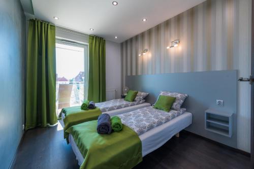 1 Schlafzimmer mit 2 Betten, grünen Vorhängen und einem Fenster in der Unterkunft Apartament Marina View in Giżycko