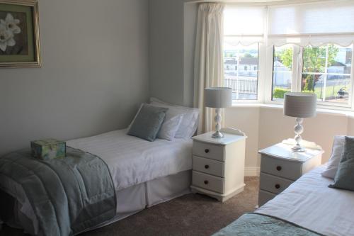 een slaapkamer met 2 bedden en een raam bij 5 mins walk to Carrick - Sleeps 12 - Off road parking - Modern house in Carrick on Shannon