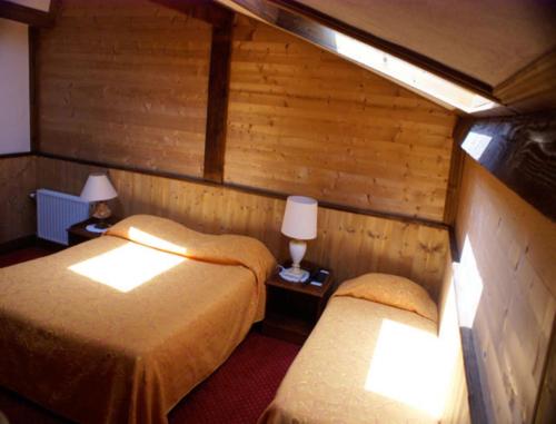 2 camas en una habitación con paredes de madera y 2 lámparas en Le Relais de l'Abbaye, en Tournus