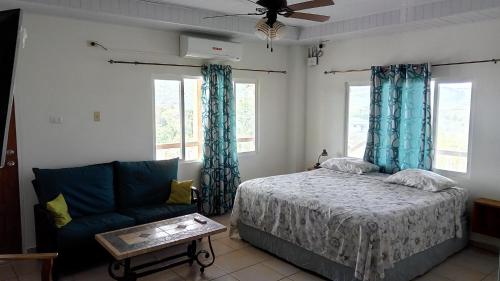a bedroom with a bed and a couch and windows at Michael's Tropical Suites in Scarborough