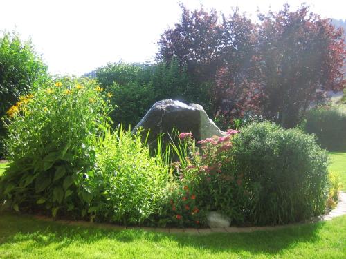 a garden with a rock and flowers in the grass at Apart Daniela in Fiss