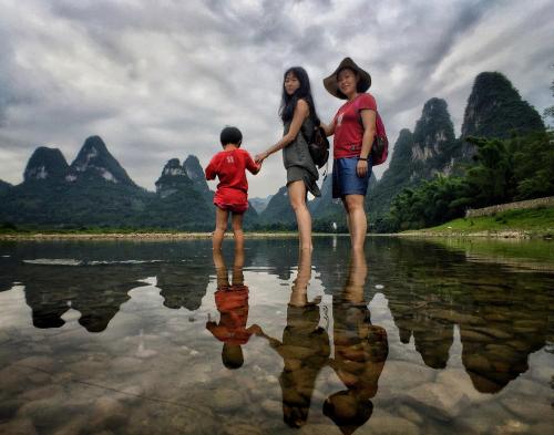 a family walking on the water in the li river at Yangshuo Yunshe Mountain Guesthouse in Yangshuo