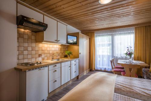 a kitchen with white cabinets and a table and a window at otto steiner appartements pension ellmau & wilder kaiser in Ellmau