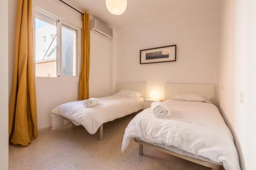2 Betten in einem Zimmer mit Fenster in der Unterkunft TRIANA WITH FREE PARKING in Sevilla