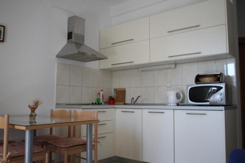 a kitchen with white cabinets and a table and a microwave at Villa Srima in Vodice