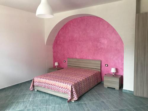 een slaapkamer met een roze bed en een roze muur bij Affittacamere Villa Zelinda in Sirolo