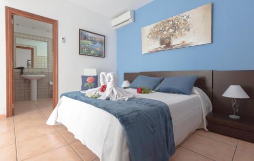 ein Schlafzimmer mit einem weißen Bett mit blauen Wänden in der Unterkunft Villa Bella Lucia 1. Piscina Climatizada, WiFi, BBQ. in Corralejo
