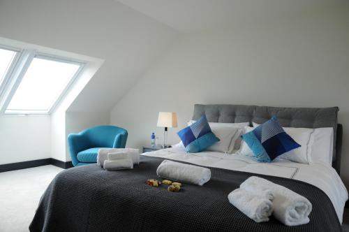 a bedroom with a large bed with towels and a blue chair at Seascapes in Inch