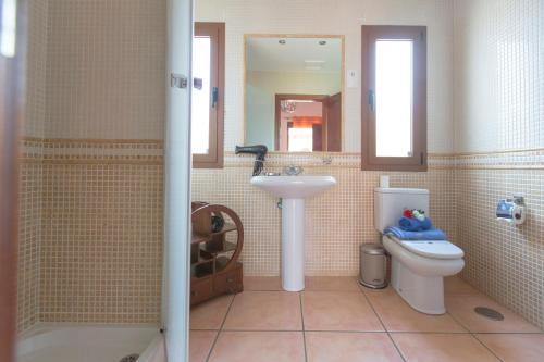 ein Badezimmer mit Waschbecken, Toilette und Spiegel in der Unterkunft Villa Bella Lucia 1. Piscina Climatizada, WiFi, BBQ. in Corralejo
