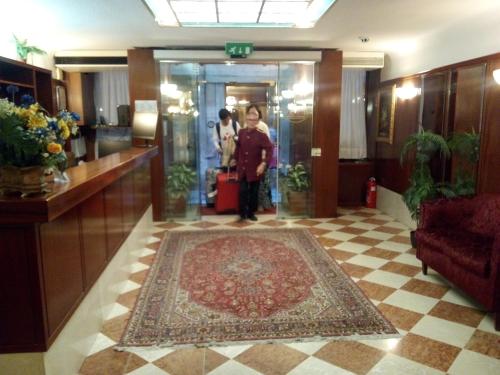 a woman is standing in a lobby with a rug at Hotel Diana in Venice