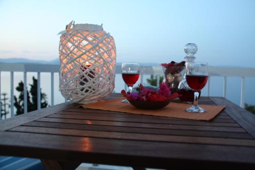 a table with two glasses of wine on a balcony at iliana's seaside maisonette in Spetses