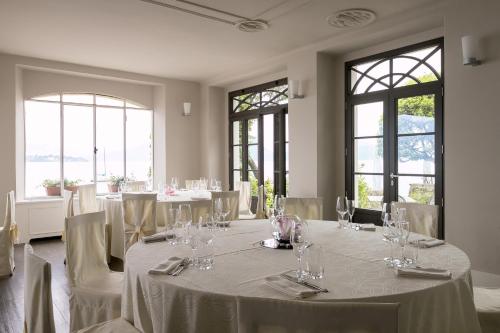 a room with white tables and chairs and windows at Belvedere in Stresa