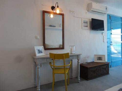escritorio con espejo y silla amarilla en Aegean Eye Apartments, en Kástron
