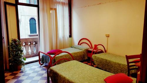 a room with four beds and a window at Ostello Domus Civica in Venice