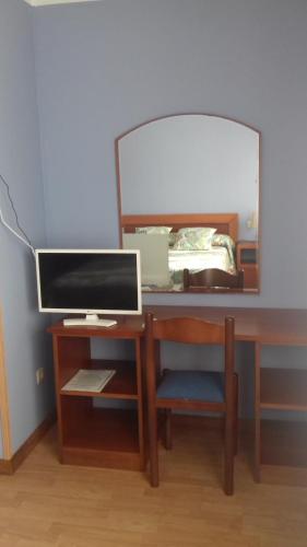a desk with a computer monitor and a mirror at Hotel Brisas del Sella in Ribadesella