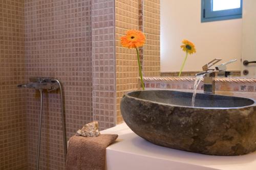 baño con un gran lavabo de piedra con flores en Villas Armeno - Maria, en Sivota