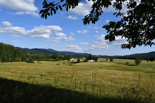 a field of grass with a house in the distance at Chalupa Chlum Míša in Volary