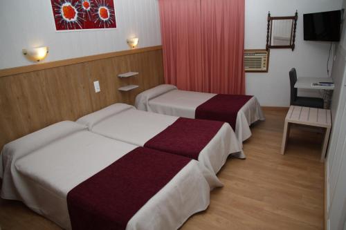 a hotel room with two beds and a table at Hotel Real Castellon in Castellón de la Plana