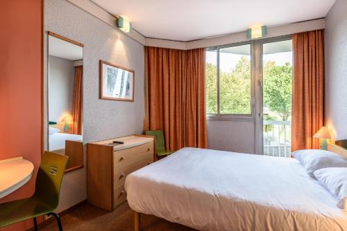 ダクスにあるMiradourのベッド、デスク、窓が備わるホテルルームです。