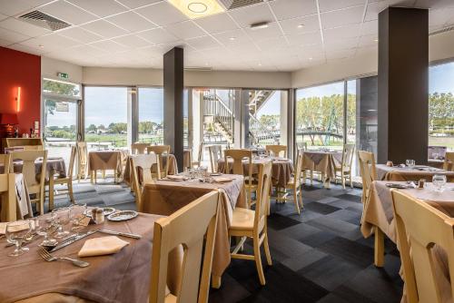 a restaurant with tables and chairs and windows at Miradour in Dax