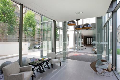 a lobby with chairs and a table and windows at Martin's Klooster in Leuven
