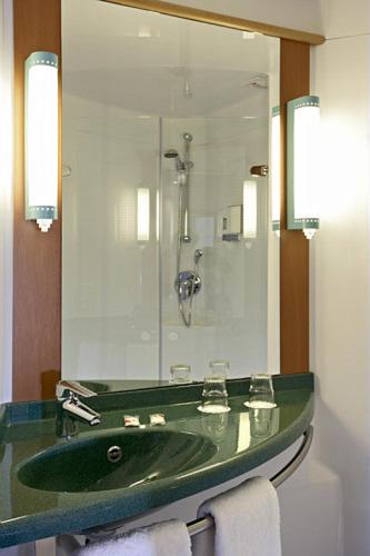 a bathroom with a green sink and a mirror at ibis Liège Seraing in Boncelles