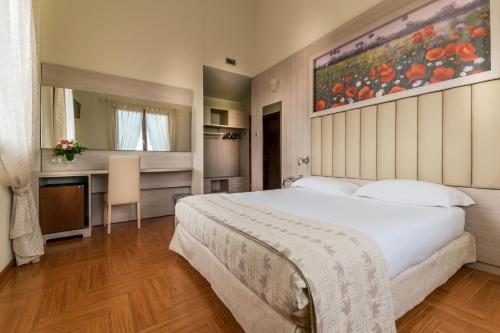 a bedroom with a large white bed and a kitchen at Hotel Tre Torri in Medolla