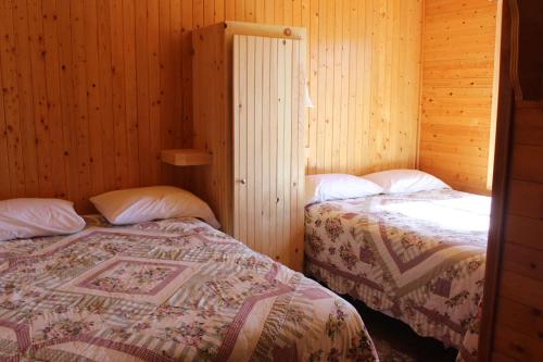 two beds in a room with wooden walls at Chalets Grand Pre Cottages in North Rustico
