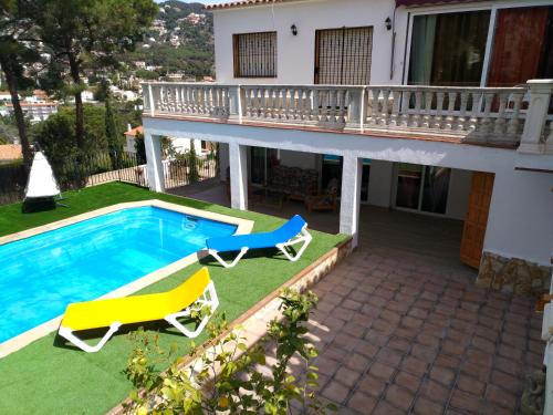 une maison avec une piscine et deux chaises longues dans l'établissement Alojamiento BOGUES, à Lloret de Mar