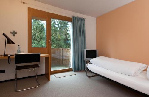 um quarto com uma cama, uma televisão e uma janela em Akademie der Dioezese em Stuttgart