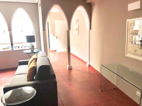 a living room with a black couch and arched windows at Nettuno Suite in Siracusa