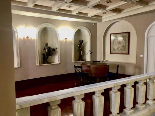 a room with a staircase with two statues on the wall at Nettuno Suite in Siracusa