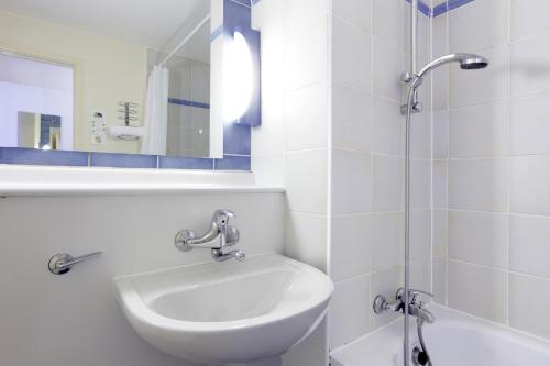 een witte badkamer met een wastafel en een douche bij Campanile Hotel & Restaurant Venlo in Venlo