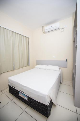 a bedroom with a white bed in a room at Vila Dumont no Centro de Foz in Foz do Iguaçu
