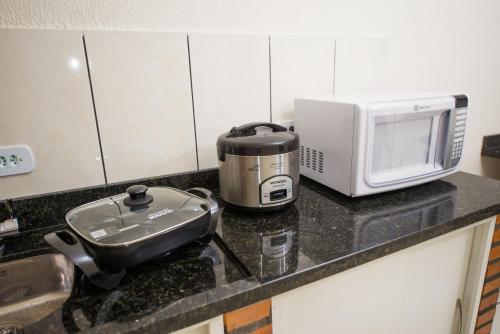 a kitchen counter with a toaster and a microwave at Vila Dumont no Centro de Foz in Foz do Iguaçu