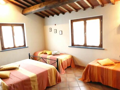 una habitación con dos camas y dos ventanas en Casa Elisa, en Montaione
