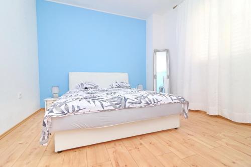 a white bedroom with a bed and a blue wall at Apartment Marjana Prižba in Prizba