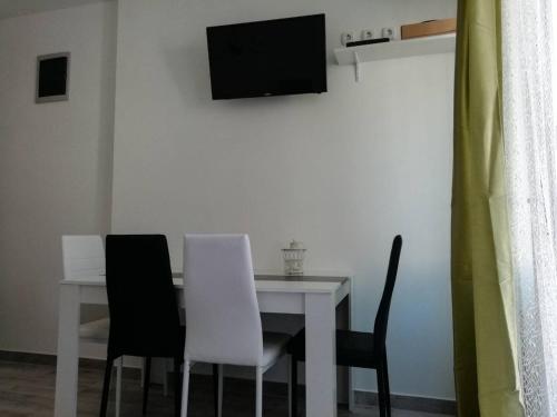 mesa de comedor con 2 sillas blancas y TV en Punta en Pula