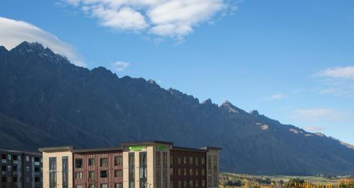 a large building with a mountain in the background at Wyndham Garden Queenstown in Queenstown