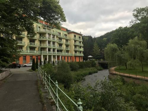 a hotel with a river in front of a building at Slunecni Lazne Apartments in Karlovy Vary