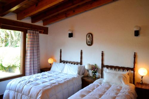 a bedroom with two beds and a window at Hotel Boutique El Campirano in Amanalco de Becerra