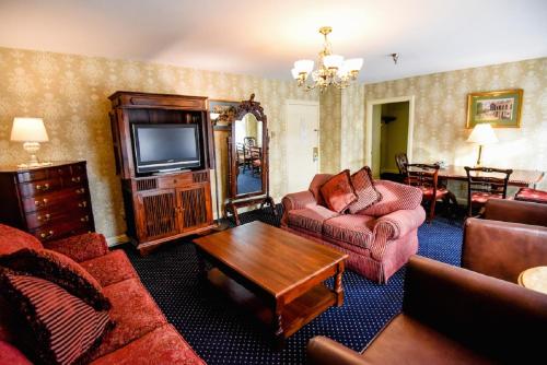 a living room with a couch and a tv at The Inn at Saratoga in Saratoga Springs