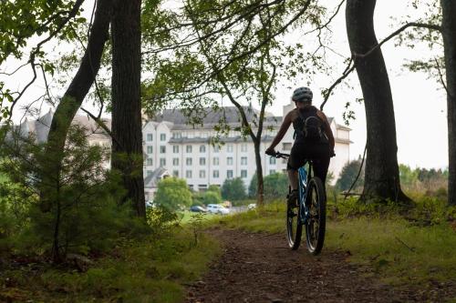a man riding a bike down a trail with a building in the background at Village Hotel on Biltmore Estate in Asheville