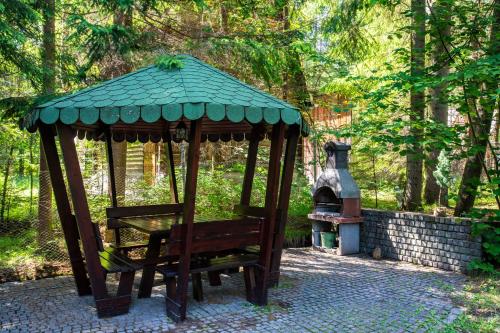 a gazebo with a bench next to a stove at Cabana Adrienne in Izvoru Mureşului