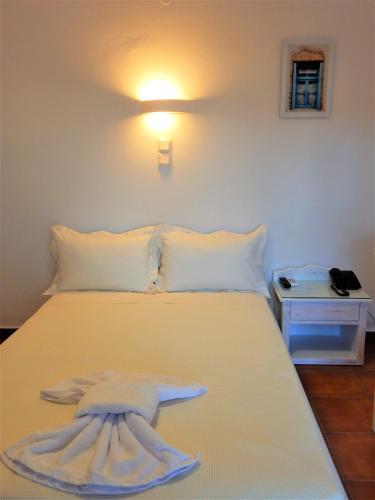 a bedroom with a white bed with a towel on it at Aegeo Hotel in Chora Folegandros
