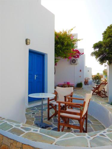 a patio with a table and chairs and a blue door at Aegeo Hotel in Chora Folegandros