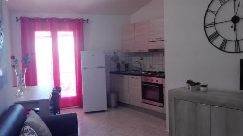 a kitchen with a white refrigerator and a clock on the wall at Casa Dolores in Baunei