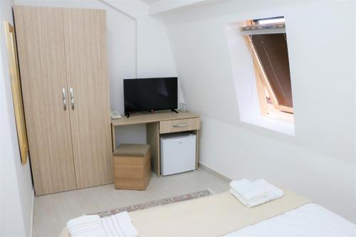 a small room with a tv and a small desk with a television at Hotel Old Konak in Skopje