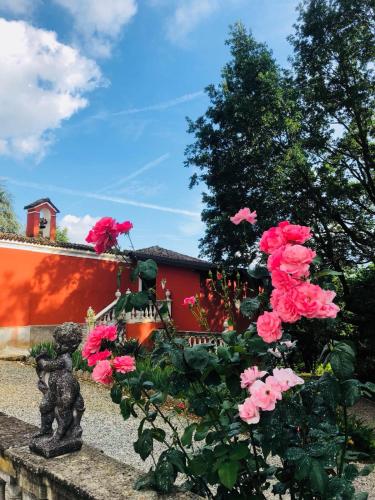 a bush of pink roses in front of a red building at Charme of Villa Capannina in Novi Ligure